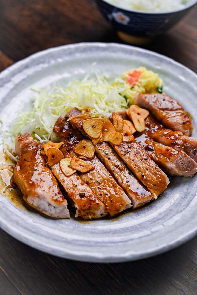 Tonteki Japanese pork steak served with fried garlic chips, shredded cabbage and potato salad