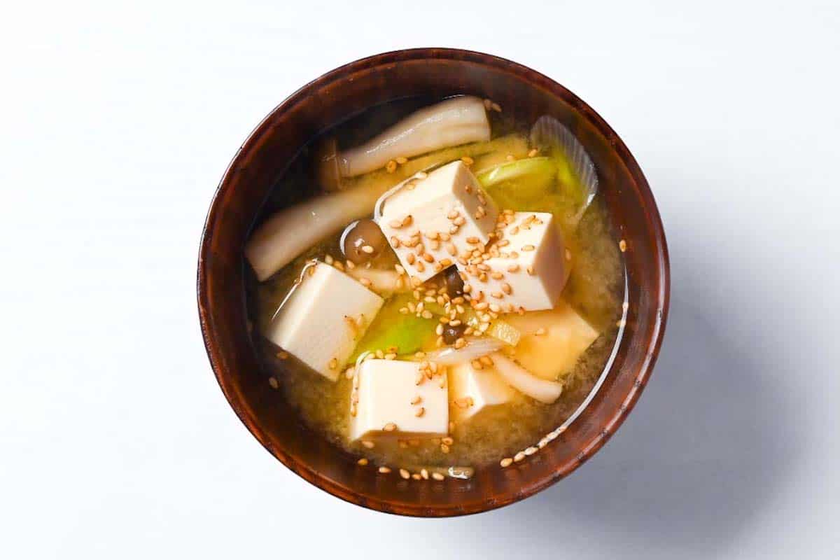 Plant based ginger miso soup in a wooden bowl and topped with sesame seeds