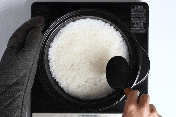 mixing cooked rice in a pot with a rice paddle