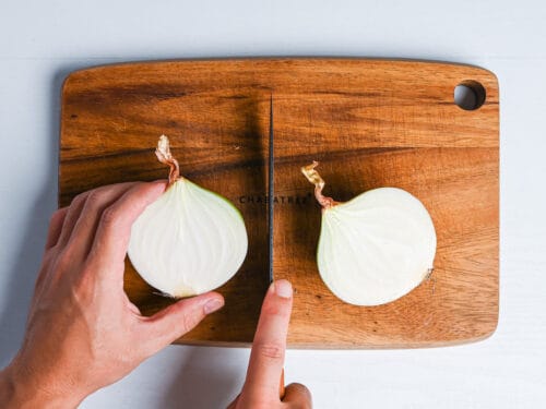 onion cut in half on a wooden chopping board