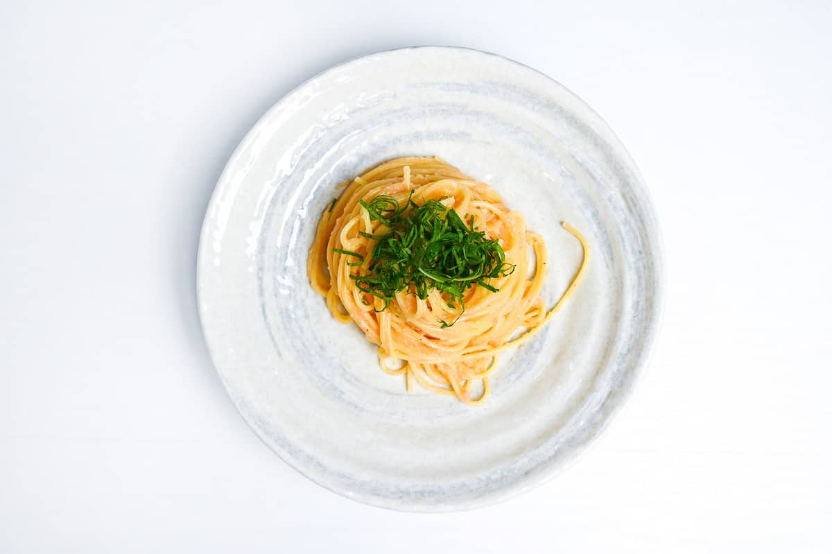 mentaiko pasta on a white and gray plate topped with shredded shiso (Perilla) leaves