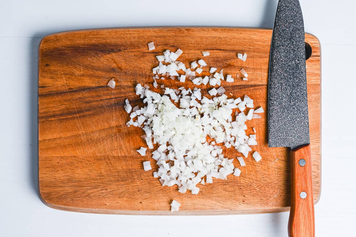 finely diced onion on a wooden chopping board with knife (mijingiri)