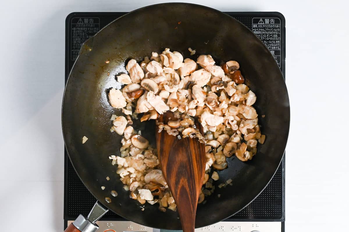 Stir frying chicken, mushrooms and onions with white wine