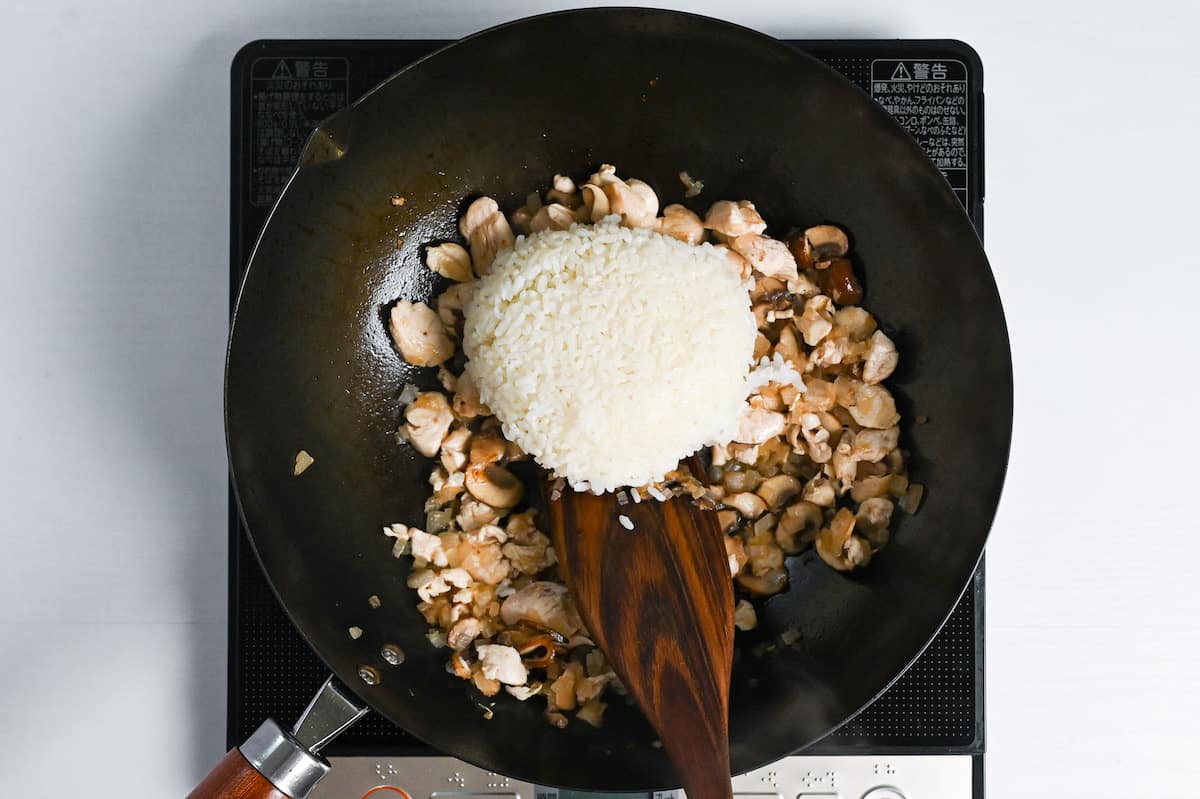 adding cooked rice to onions, chicken and mushrooms