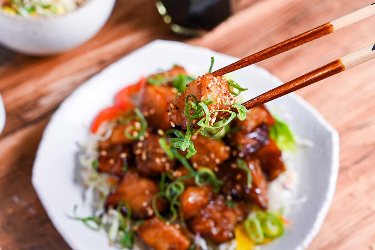 a piece of teriyaki cod held with chopsticks