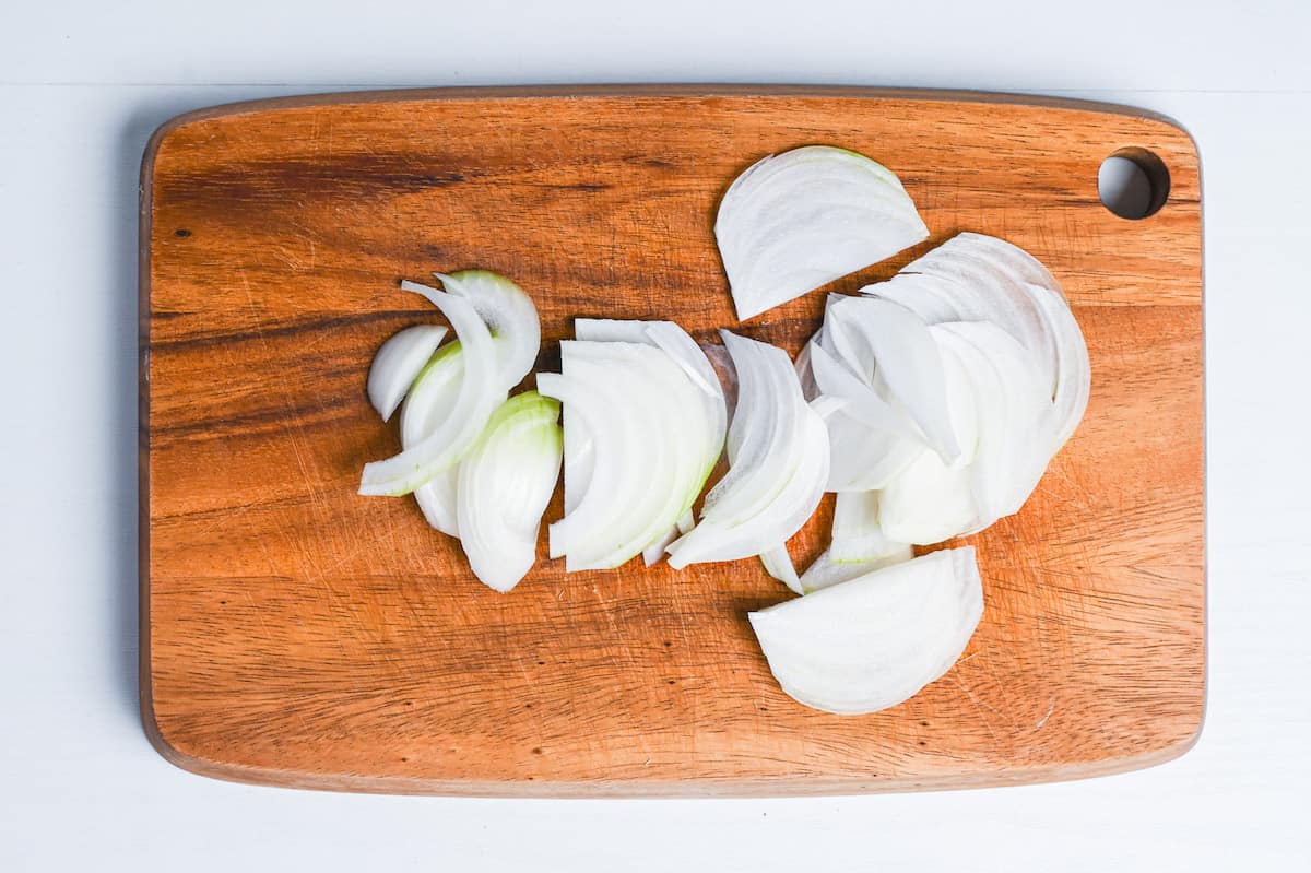 thinly sliced onion on a wooden chopping board
