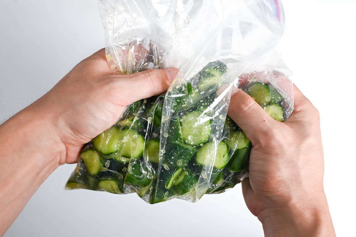 Massaging seasonings onto wasabi pickled cucumber in a ziplock bag