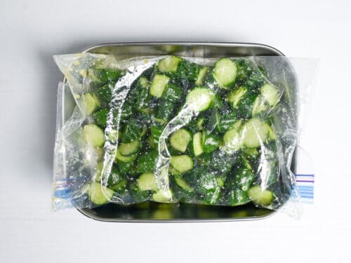 Wasabi pickled cucumber in a ziplock bag placed over a container
