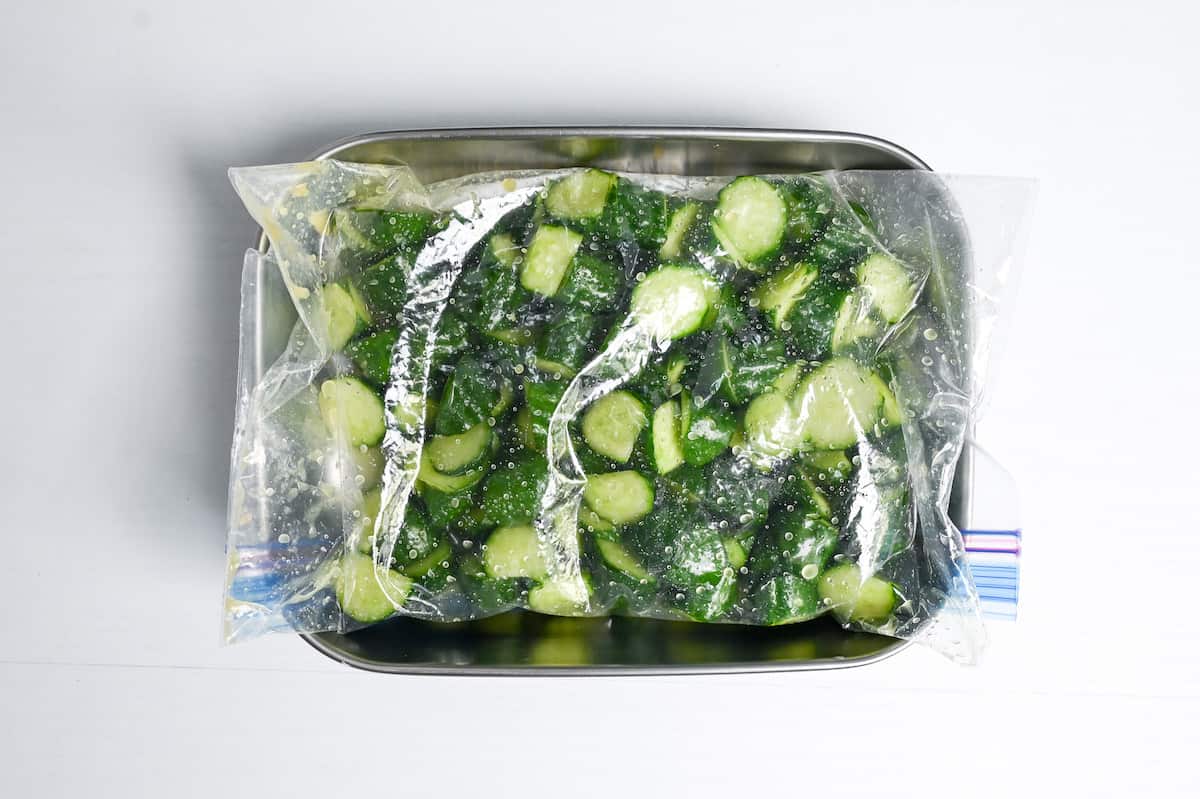 Wasabi pickled cucumber in a ziplock bag placed over a container
