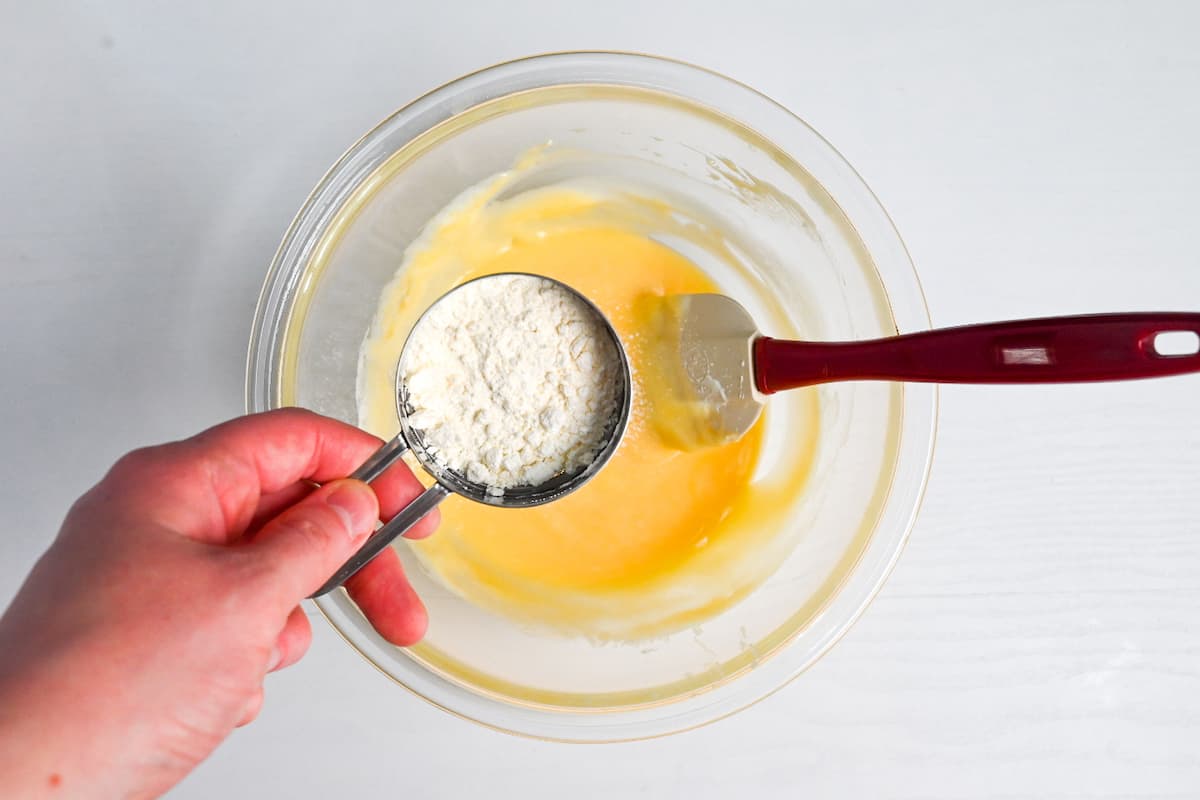 sifting flour into the cheesecake mixture