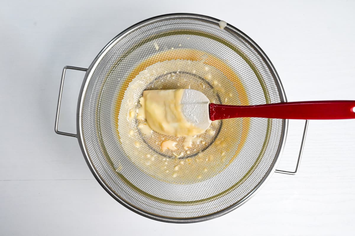 Mesh sieve placed over a large mixing bowl with the cheesecake mixture poured through