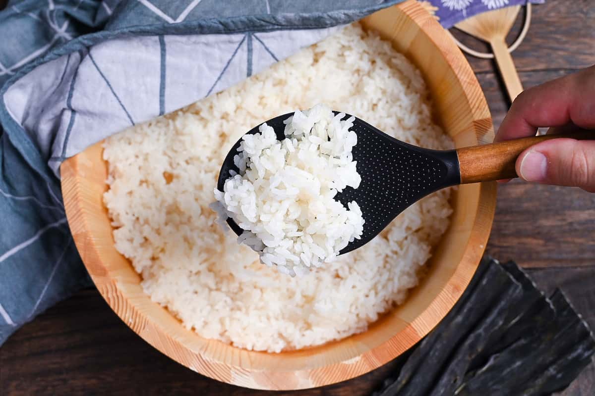 Japanese sushi rice in a sushi oke half covered with a teal tea towel