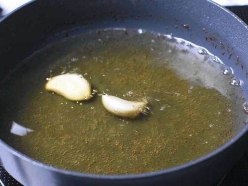 Adding garlic cloves to the oil