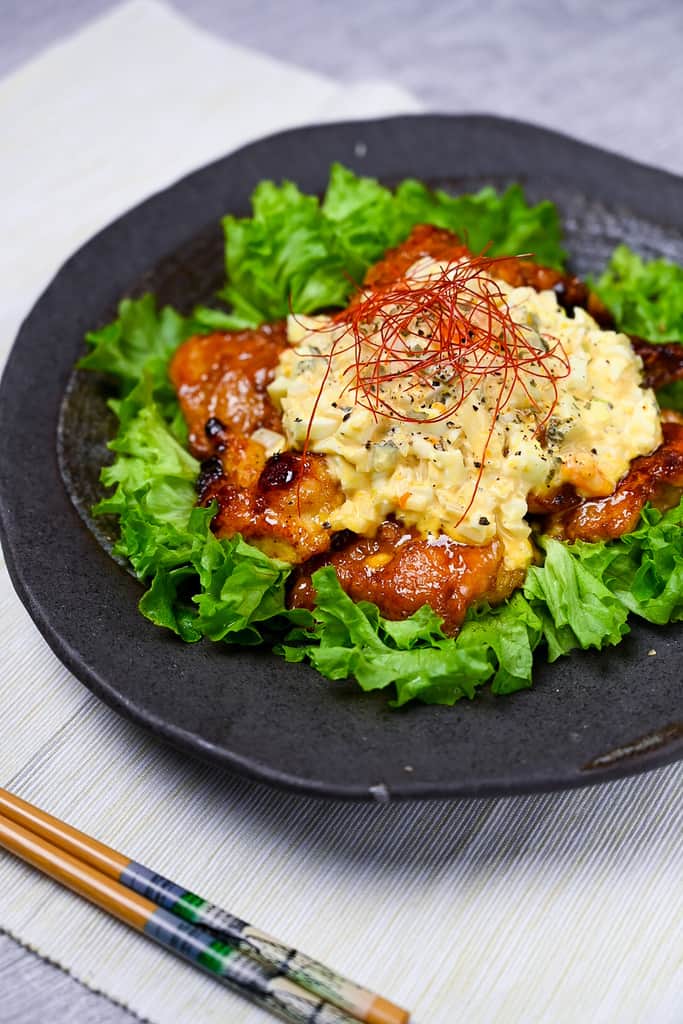 Japanese chicken nanban served on a bed of frilly lettuce on a black plate