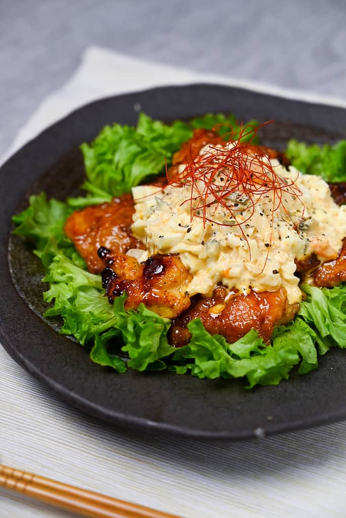 Japanese chicken nanban served on a bed of frilly lettuce on a black plate