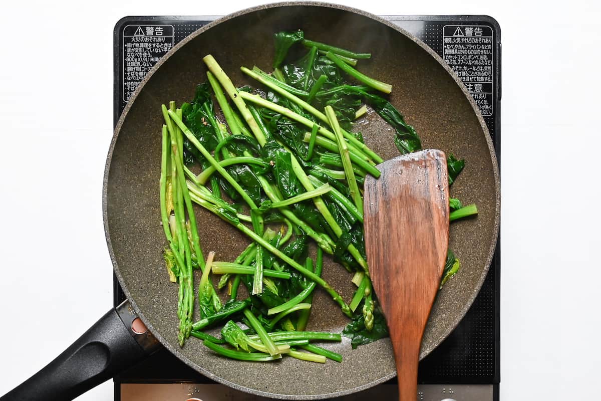 spinach and asparagus in a frying pan with butter
