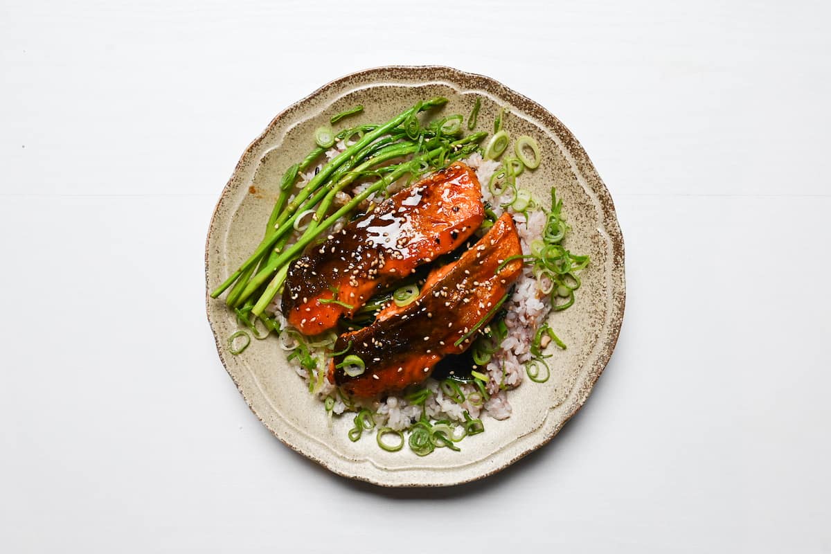 Teriyaki salmon served over multigrain rice, buttery pan fried spinach and asparagus then sprinkled with chopped spring onion and sesame seeds