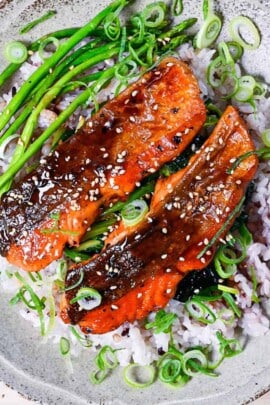 Teriyaki salmon and pan fried asparagus served over a bed a buttery spinach and mixed grain rice
