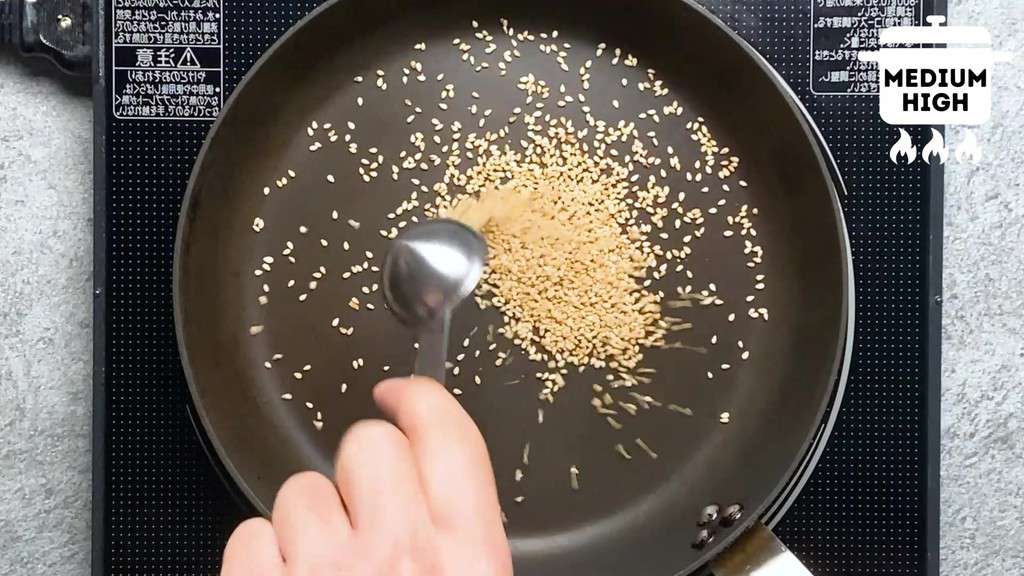Adding white sesame seeds to a pan