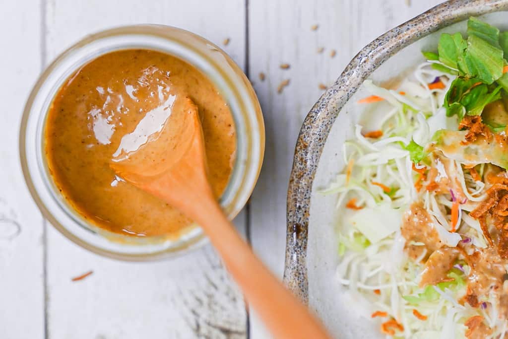 Japanese sesame dressing in a small jar with a wooden spoon top down