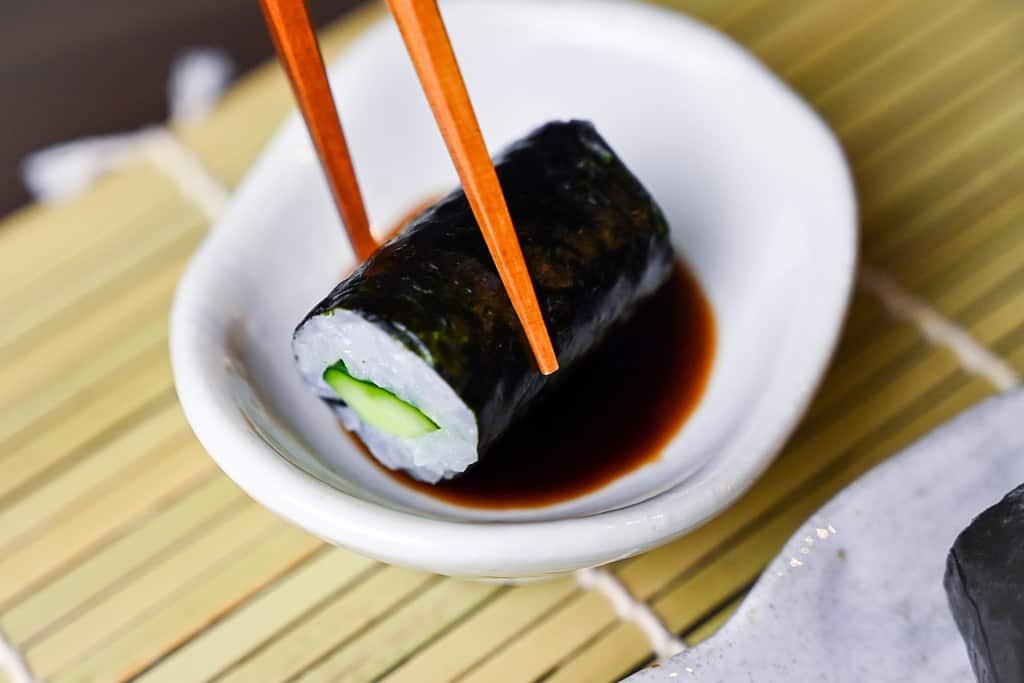 One kappa maki roll dipped in soy sauce