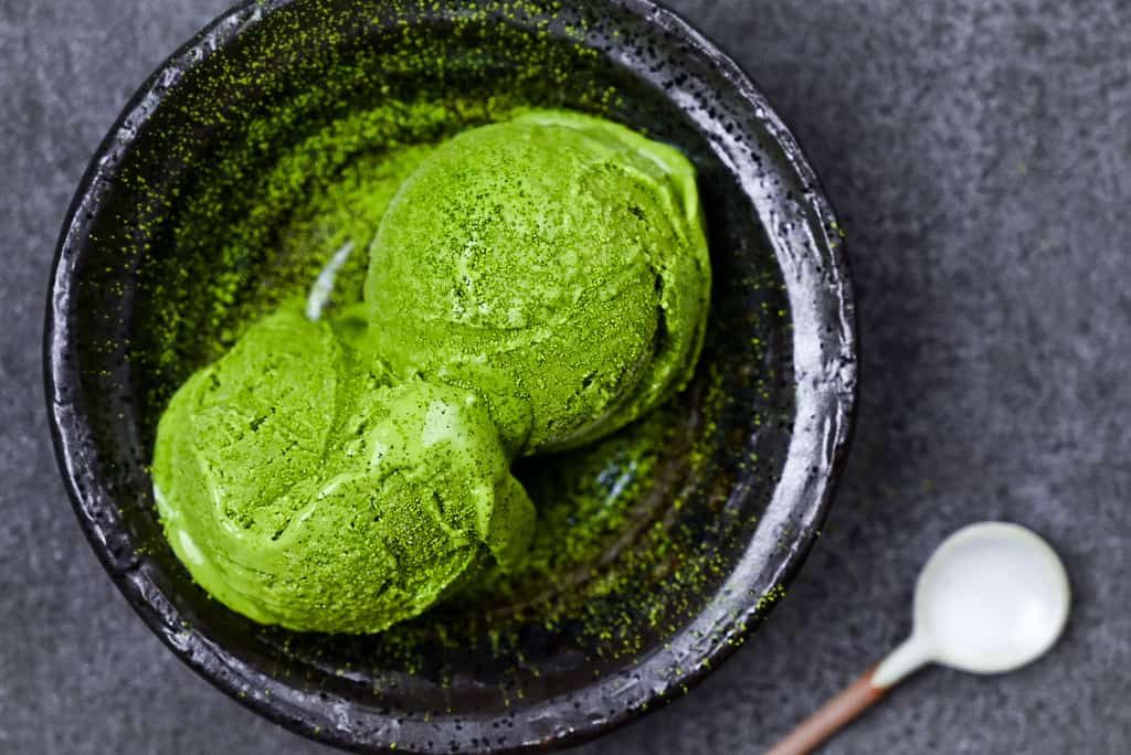 two scoops of matcha green tea ice cream served in a black bowl top down