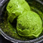 two scoops of matcha green tea ice cream served in a black bowl close up