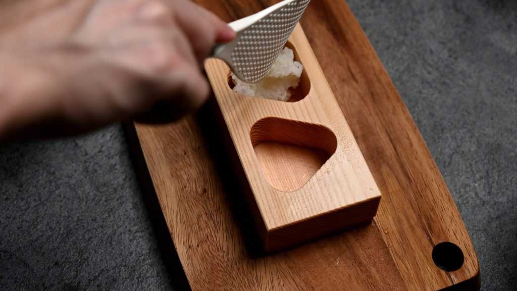 pushing rice into a wooden onigiri mold