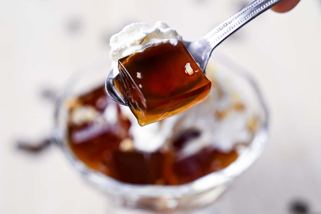 Coffee jelly with cream on a silver spoon