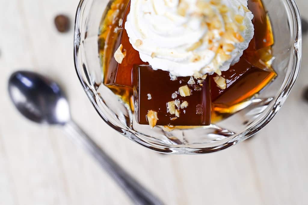 Japanese coffee served in a glass dish with whipped cream and chopped walnuts top down close up