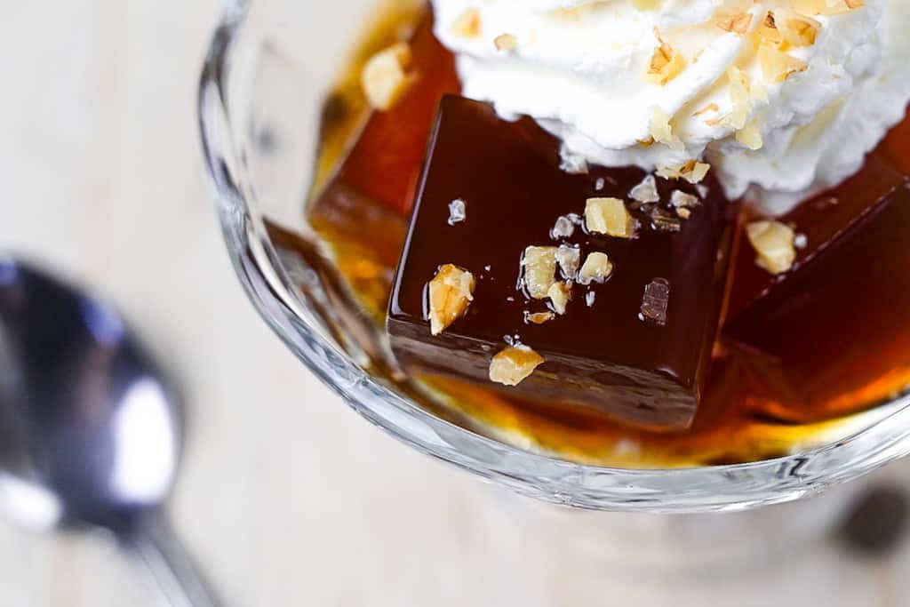 Japanese coffee served in a glass dish with whipped cream and chopped walnuts close up