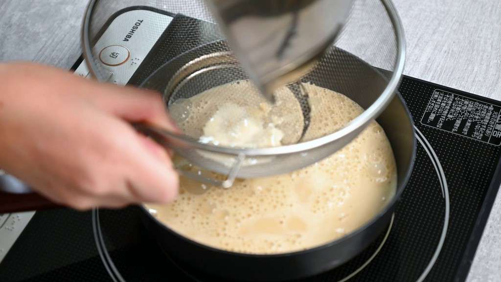 pouring ice cream custard mixture through sieve