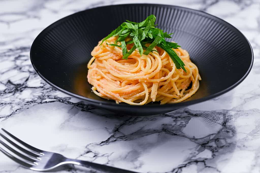 mentaiko pasta served in a black pasta dish side view
