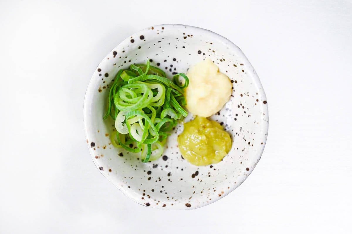 chopped green onion, grated ginger and wasabi paste in a speckled bowl