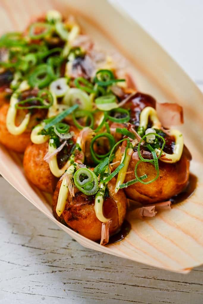 Japanese takoyaki fried octopus balls served in a bamboo boat and loaded with toppings