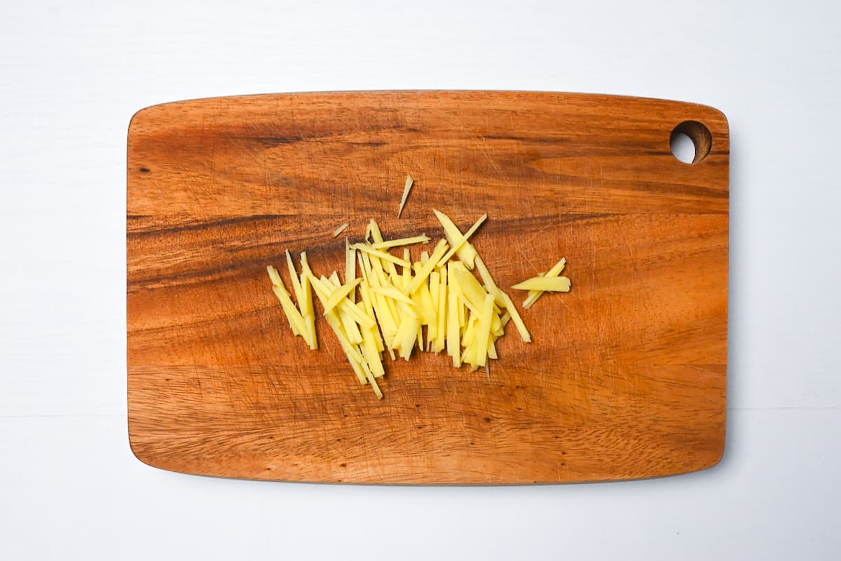 Julienned ginger on a wooden chopping board