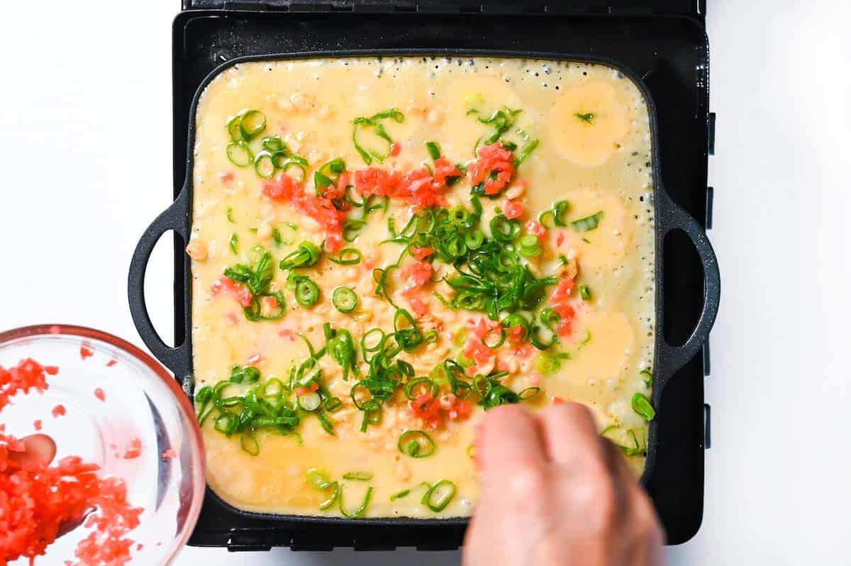 Sprinkling takoyaki batter with benishoga and chopped spring onion