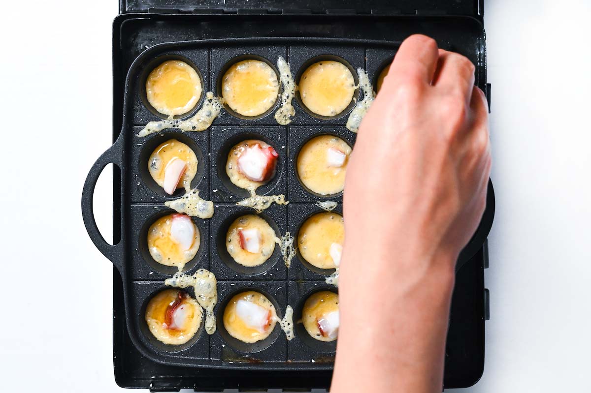 Adding octopus to each takoyaki groove