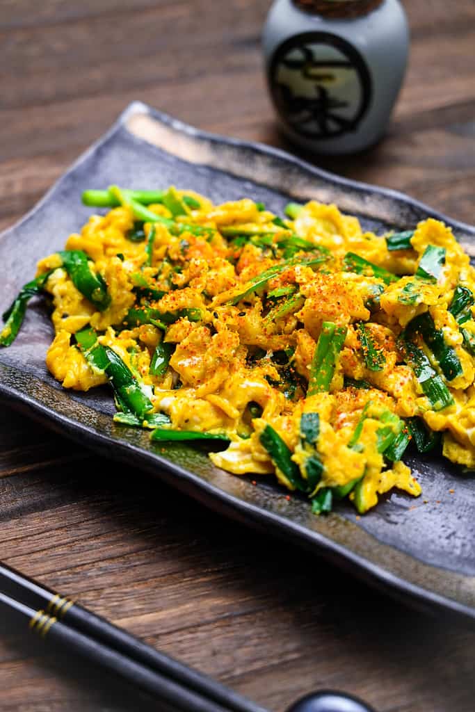 Japanese niratama egg and chive on a black plate sprinkled with shichimi