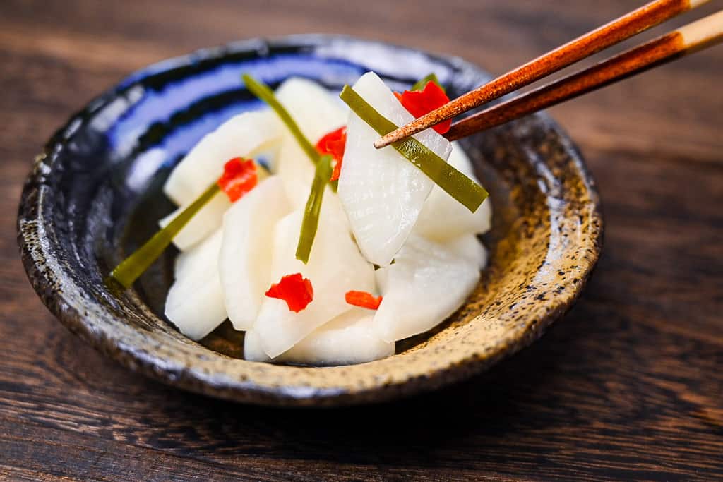 Bettarazuke pickled daikon held with wooden chopsticks