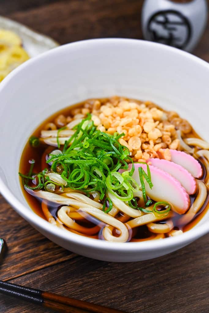 Udon noodles in a light dashi broth served in a white bowl with toppings