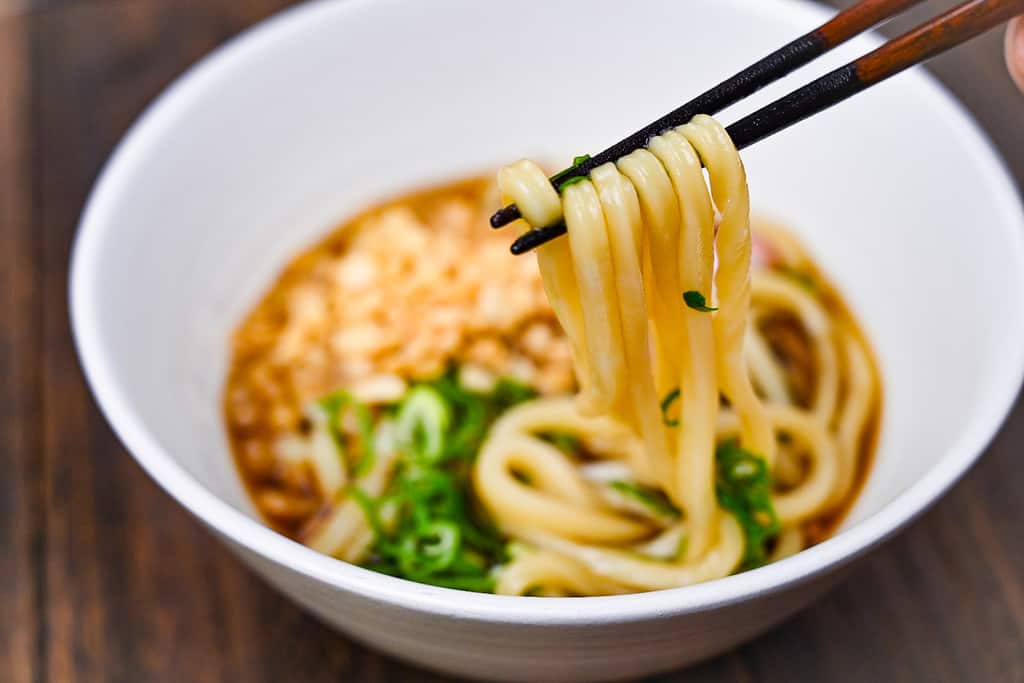 Udon noodles held with wooden chopsticks