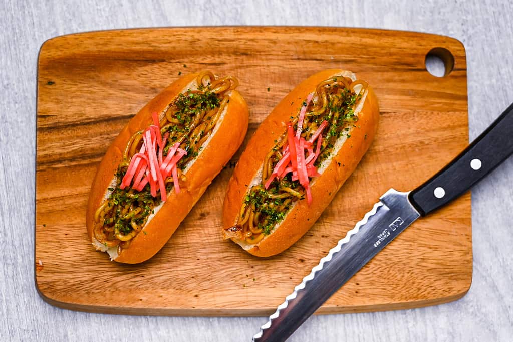 two yakisoba pans on wooden chopping board top down view