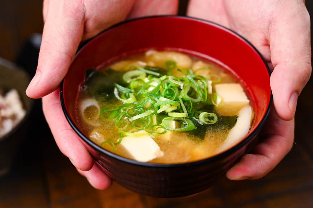 Holding Japanese Miso Soup in a red bowl