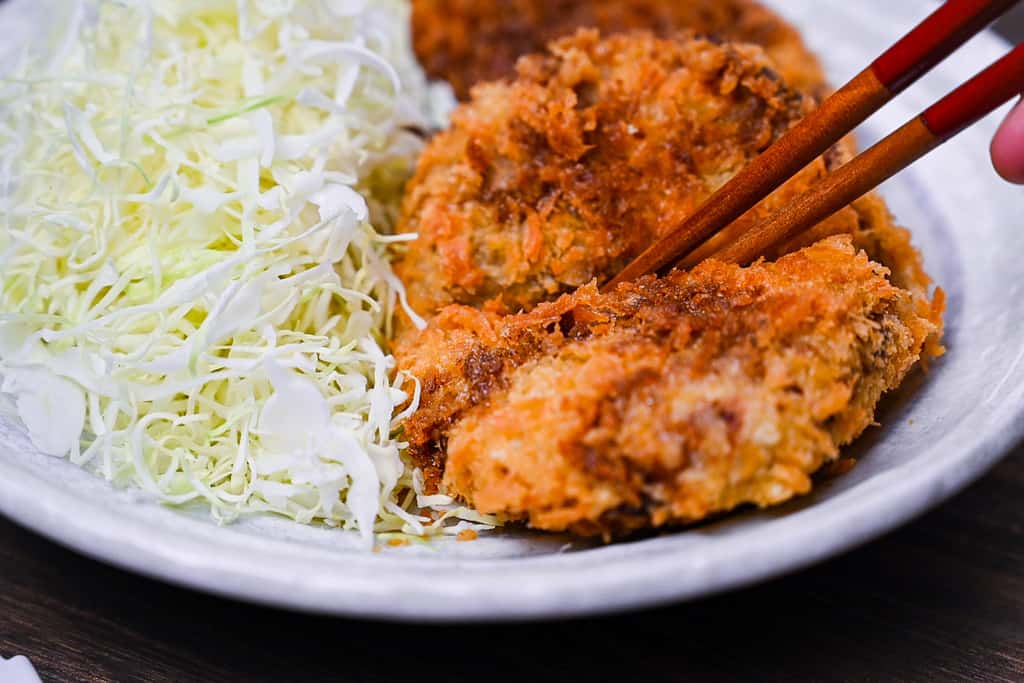 Cutting Japanese meat and potato korokke with chopsticks