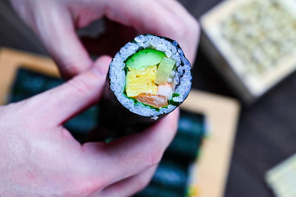 Holding one ehomaki sushi roll