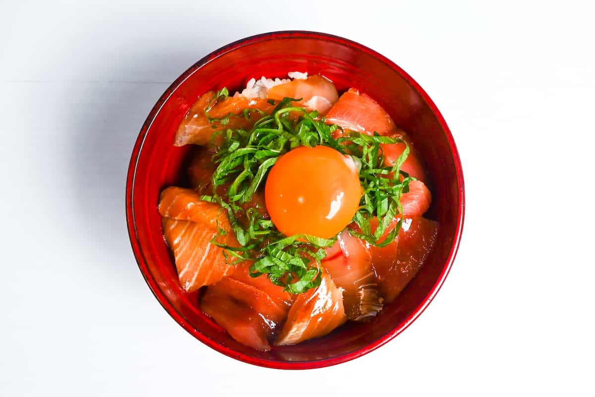 Maguro zuke don made with marinated tuna sashimi served over rice and topped with shiso leaves and an egg yolk