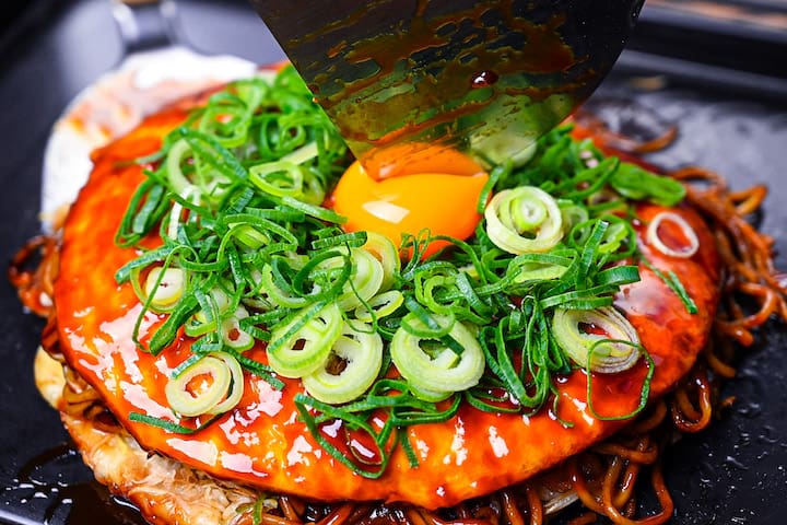 Cutting Hiroshima style okonomiyaki with a spatula