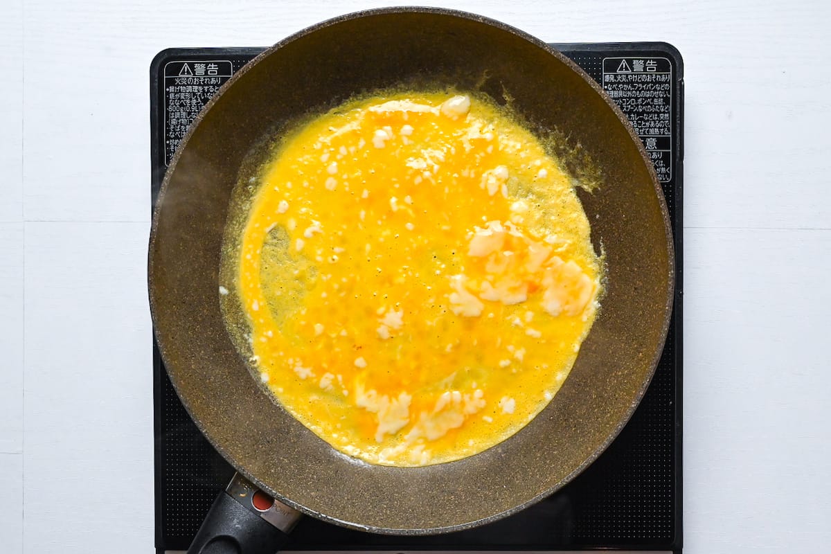 Cooking a thin egg crepe in a large frying pan