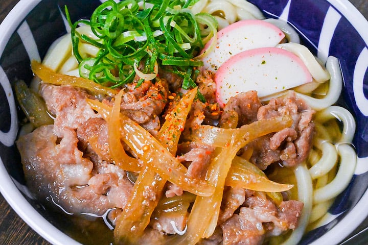 Pork udon noodle soup with pork belly, onions and kamaboko
